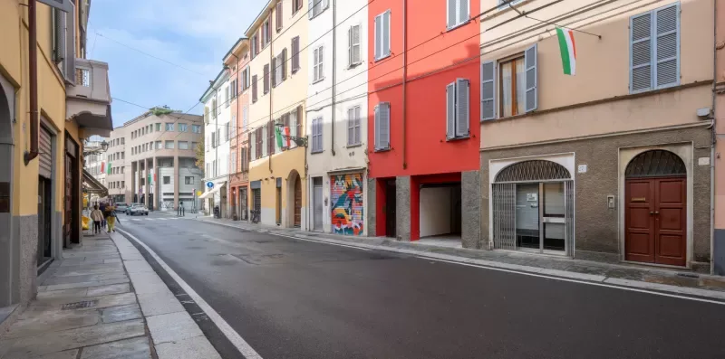 Una calle urbana flanqueada por edificios de varias plantas y comercios.