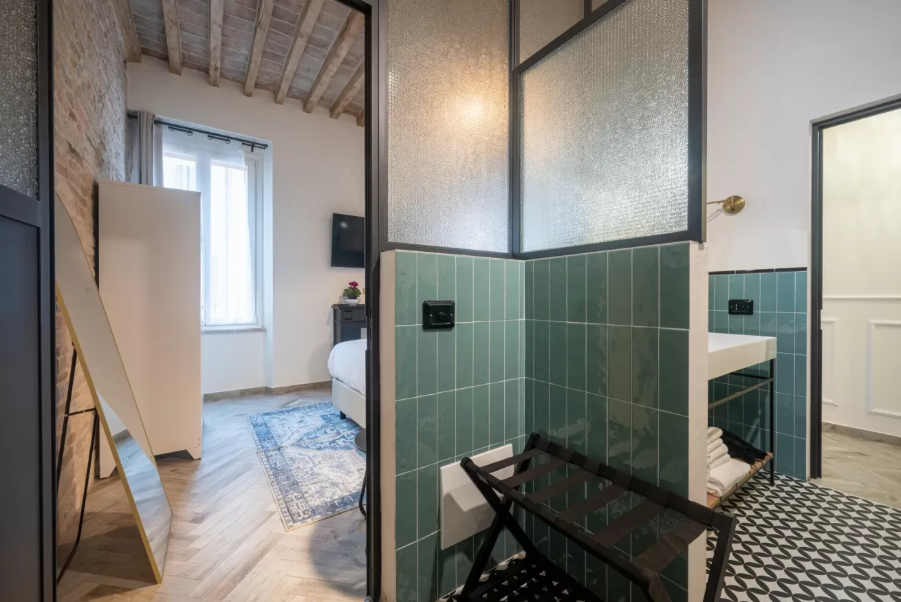 Un dormitorio se abre a un baño con azulejos, una cama y un panel de vidrio.