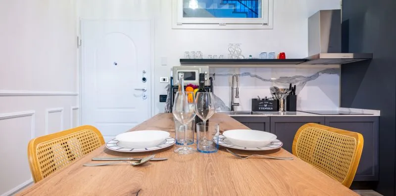 Una mesa de comedor con platos puestos está junto a una cocina compacta.