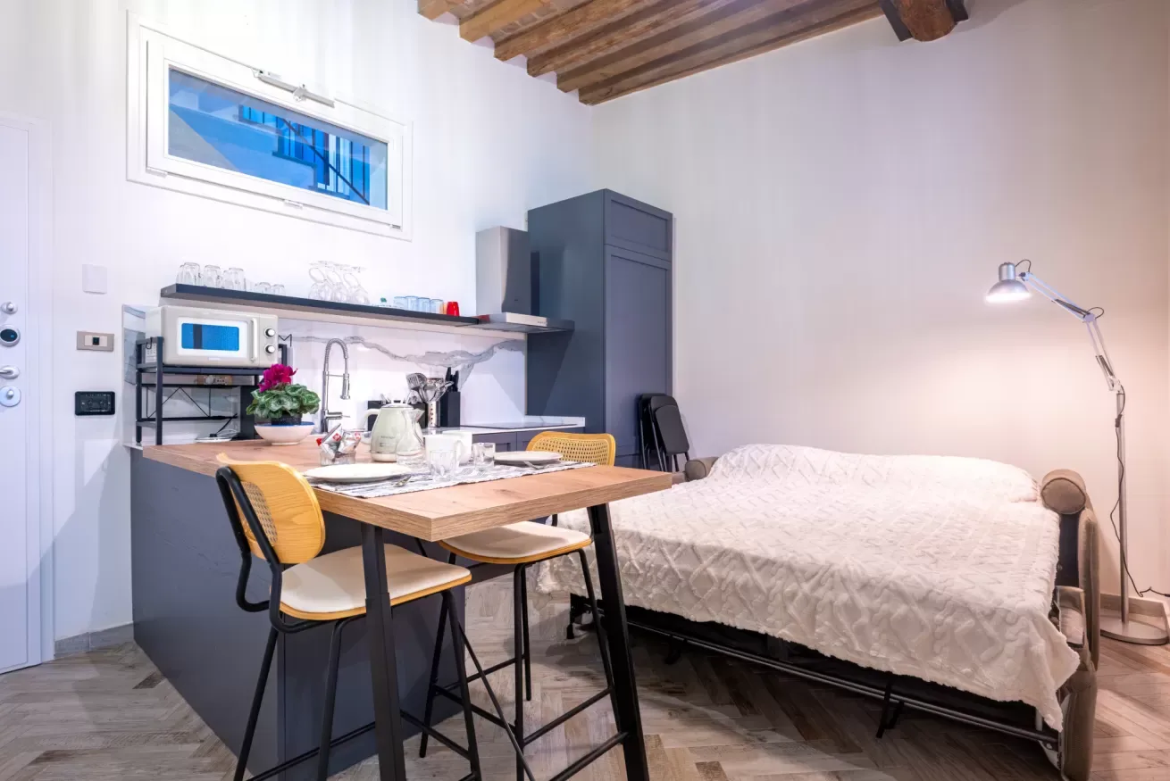 Un dormitorio compacto con cocina pequeña y una mesa junto a la cama.
