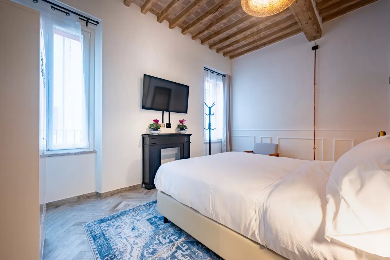 Un dormitorio con una cama grande, un televisor y vigas de madera a la vista.
