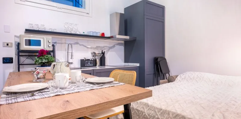 Una habitación compacta combina una mesa de comedor, una pequeña cocina y una cama.