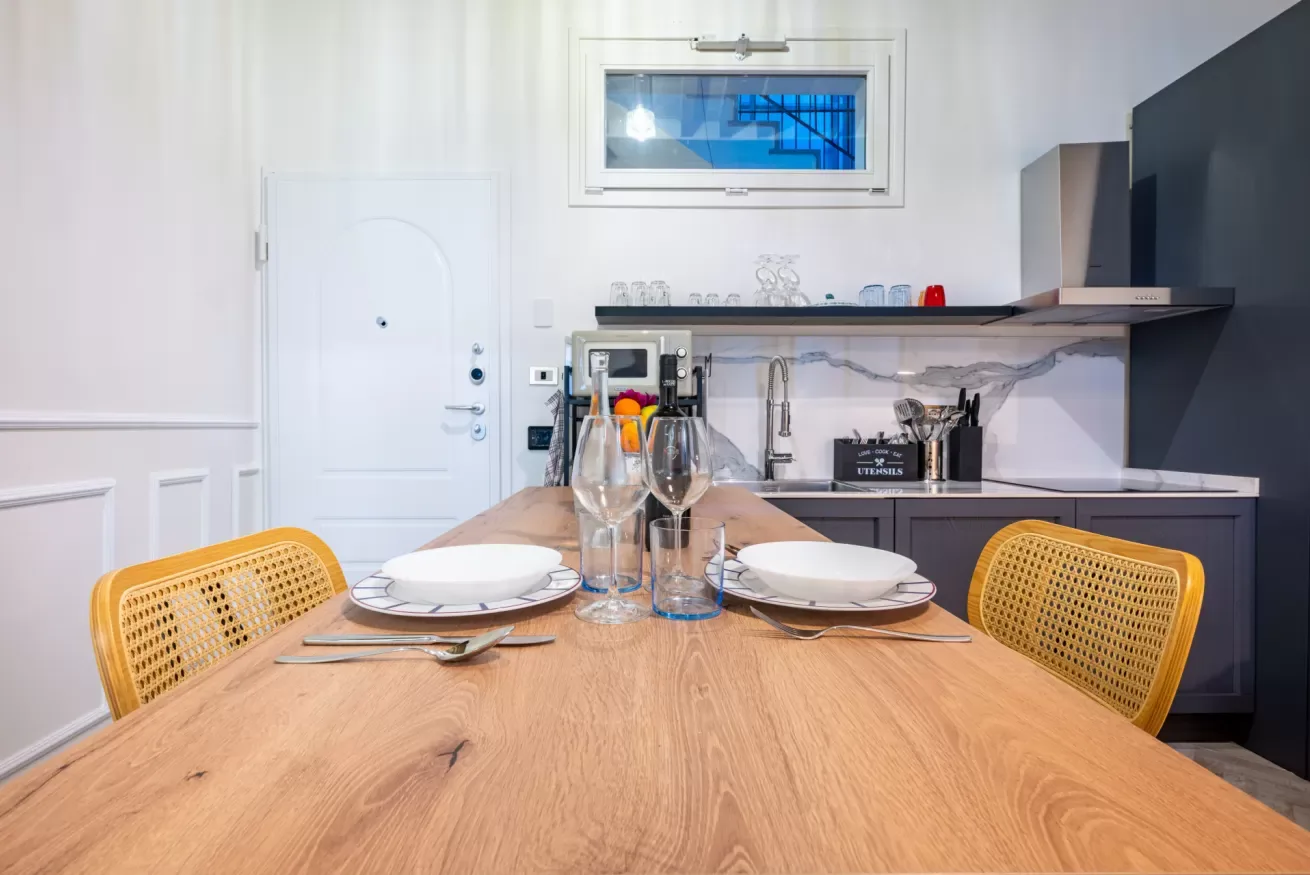 Una mesa puesta con platos y vasos está frente a una cocina compacta.