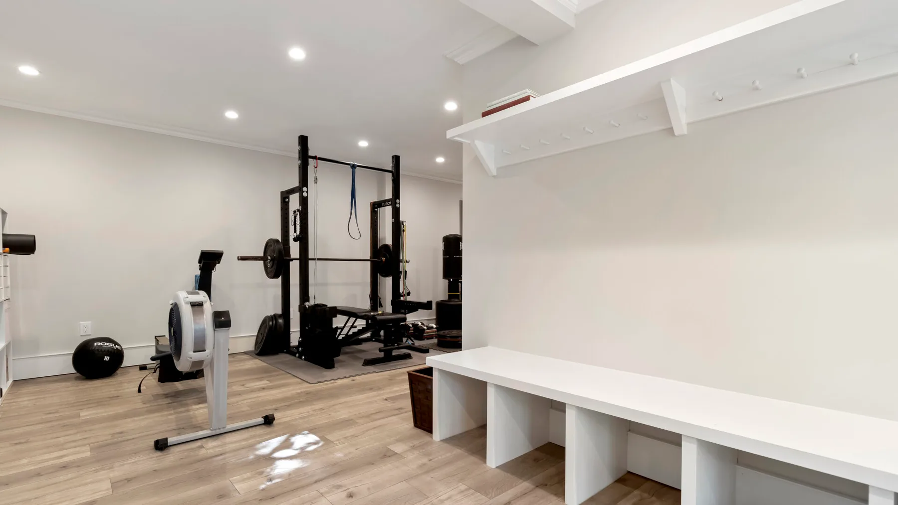 Un gimnasio en casa con equipo de ejercicio y una larga encimera blanca.