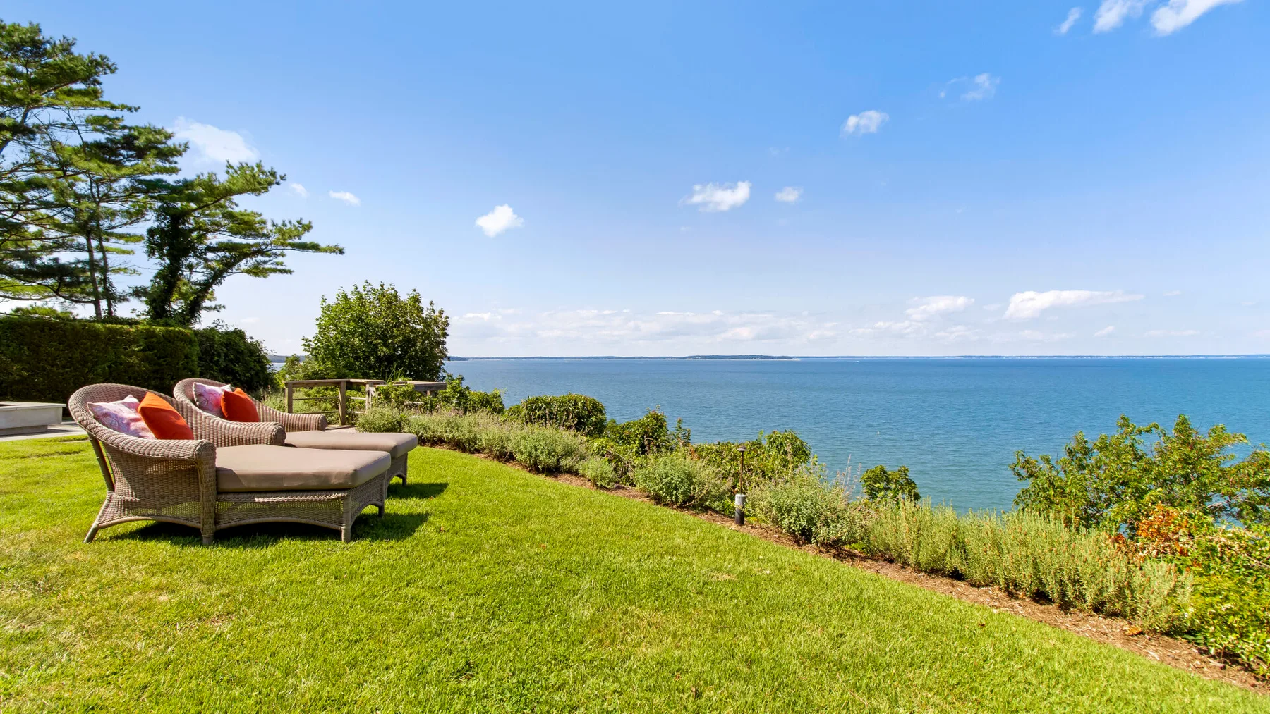 Un jardín junto al agua tiene asientos al aire libre con vistas al mar.