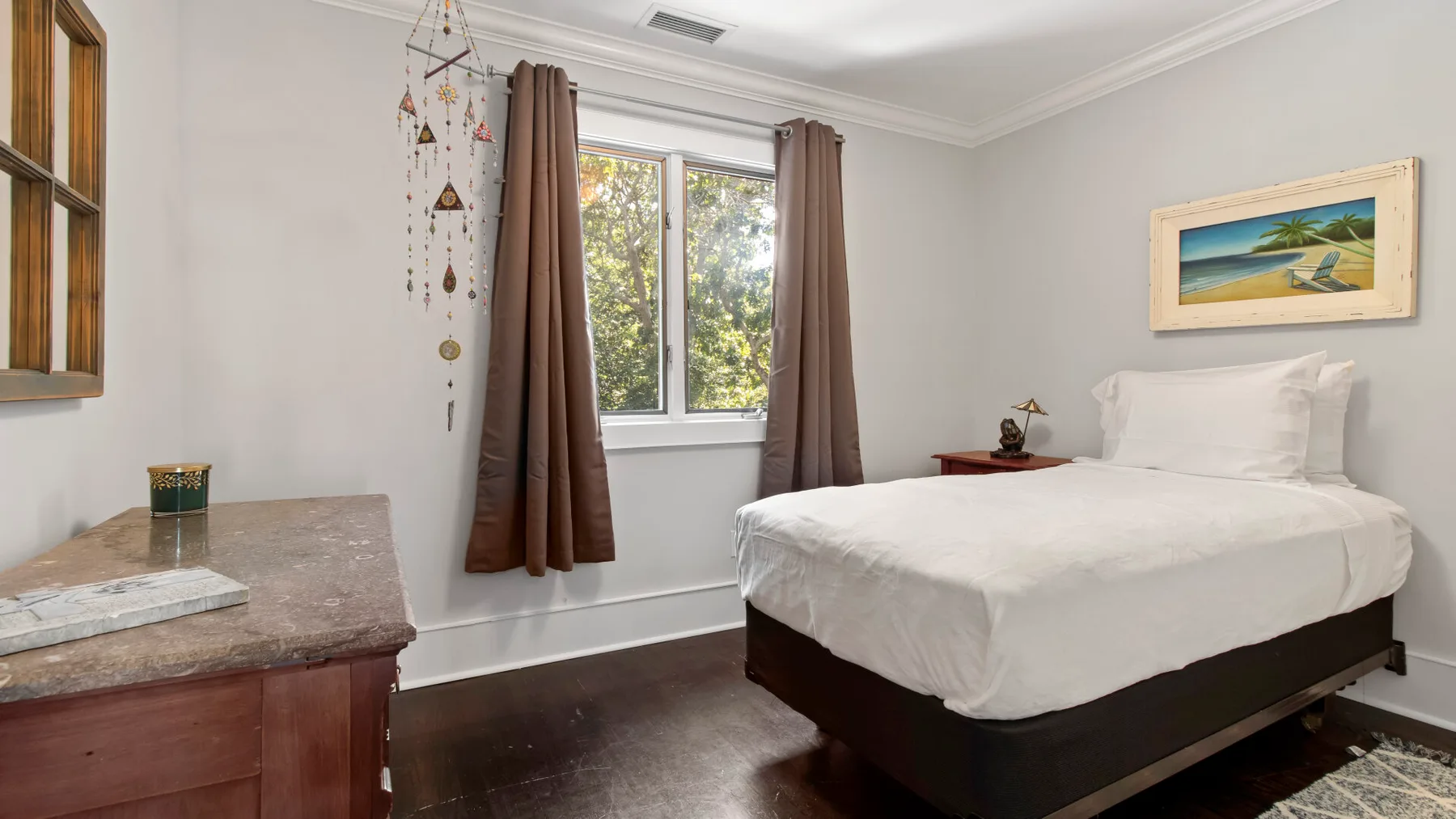 Un dormitorio con una cama bien tendida y una ventana enmarcada por cortinas.