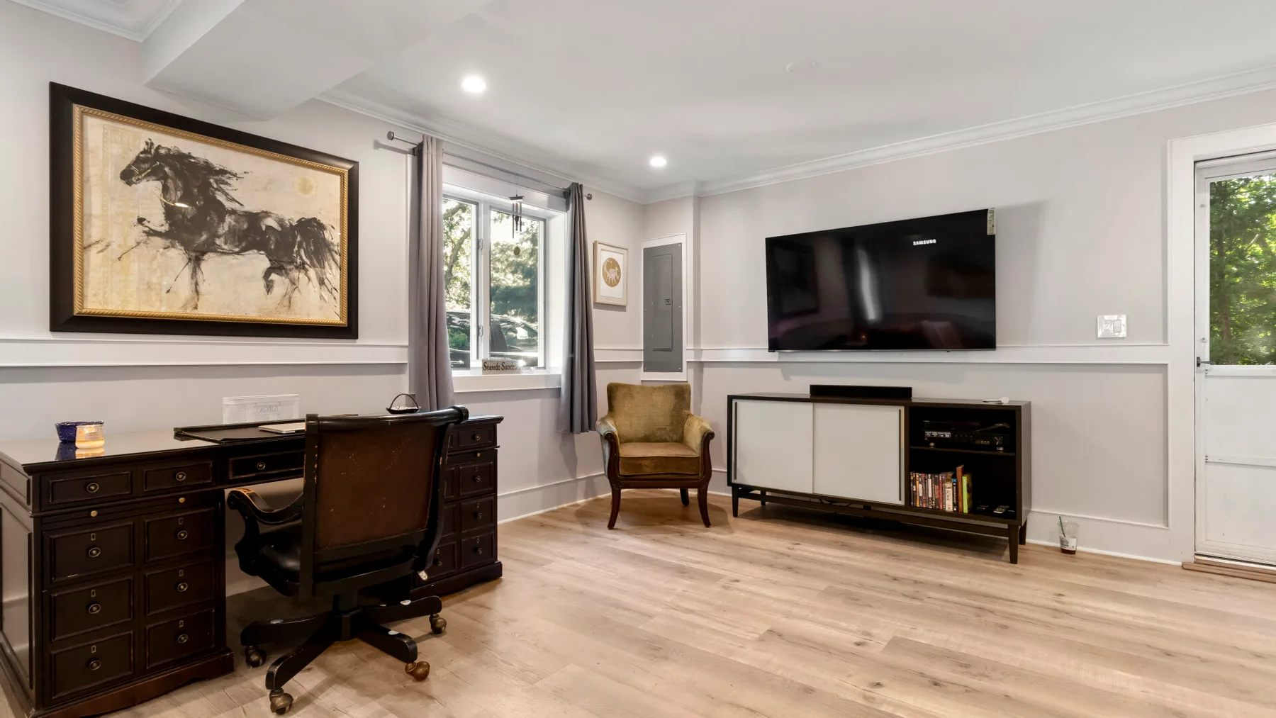 Una sala luminosa con escritorio, televisor y asientos.