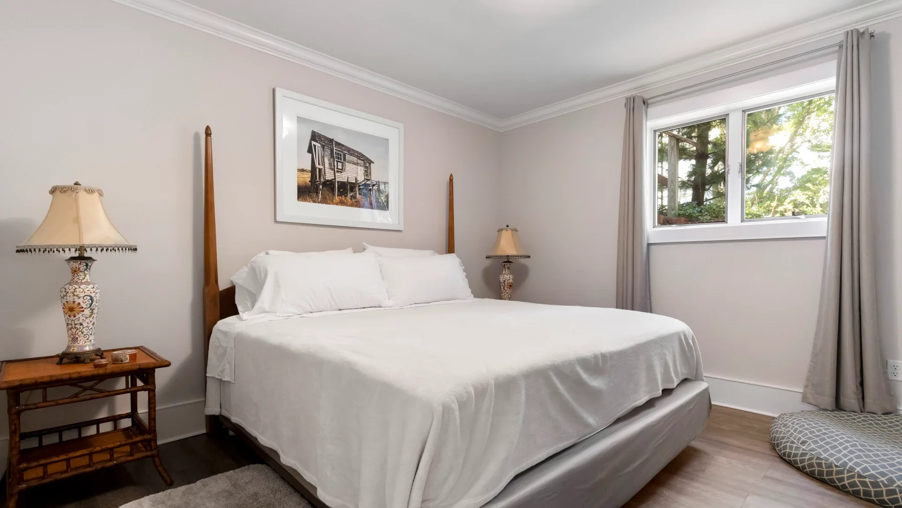 Un dormitorio con una cama bien hecha y una ventana grande.