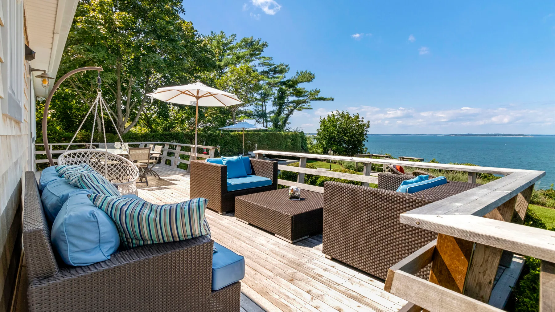 Una terraza junto al agua con asientos al aire libre, cojines azules y vistas despejadas.