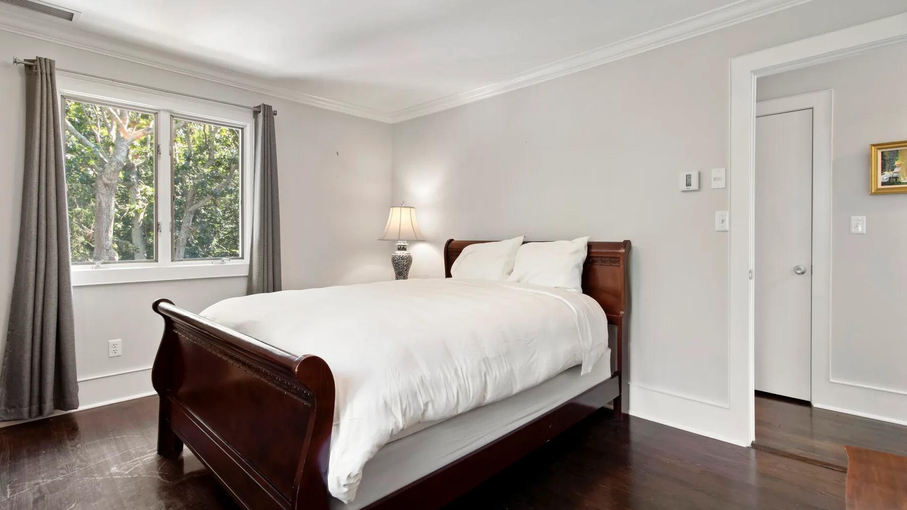 Un dormitorio con una cama bien hecha junto a una ventana.