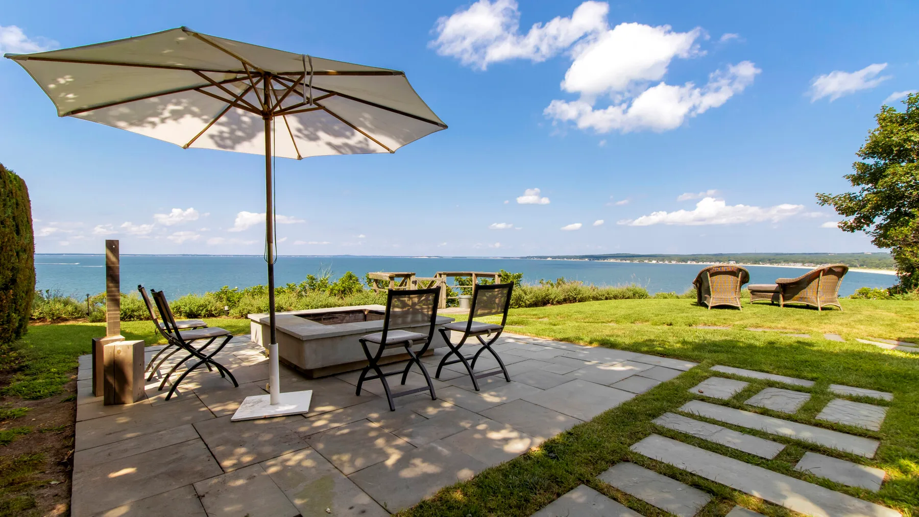 Un patio junto al mar con asientos al aire libre y una sombrilla da al agua.