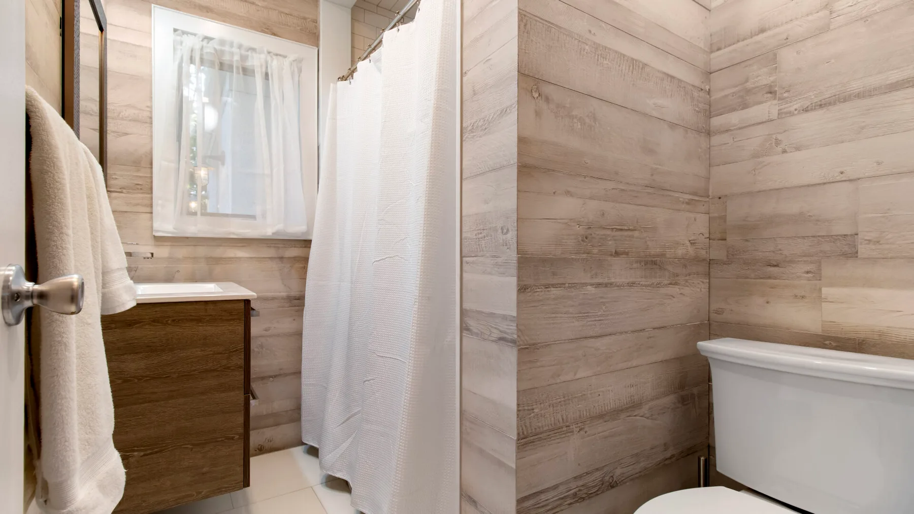 Un baño revestido de madera con cortina de ducha y bañera.