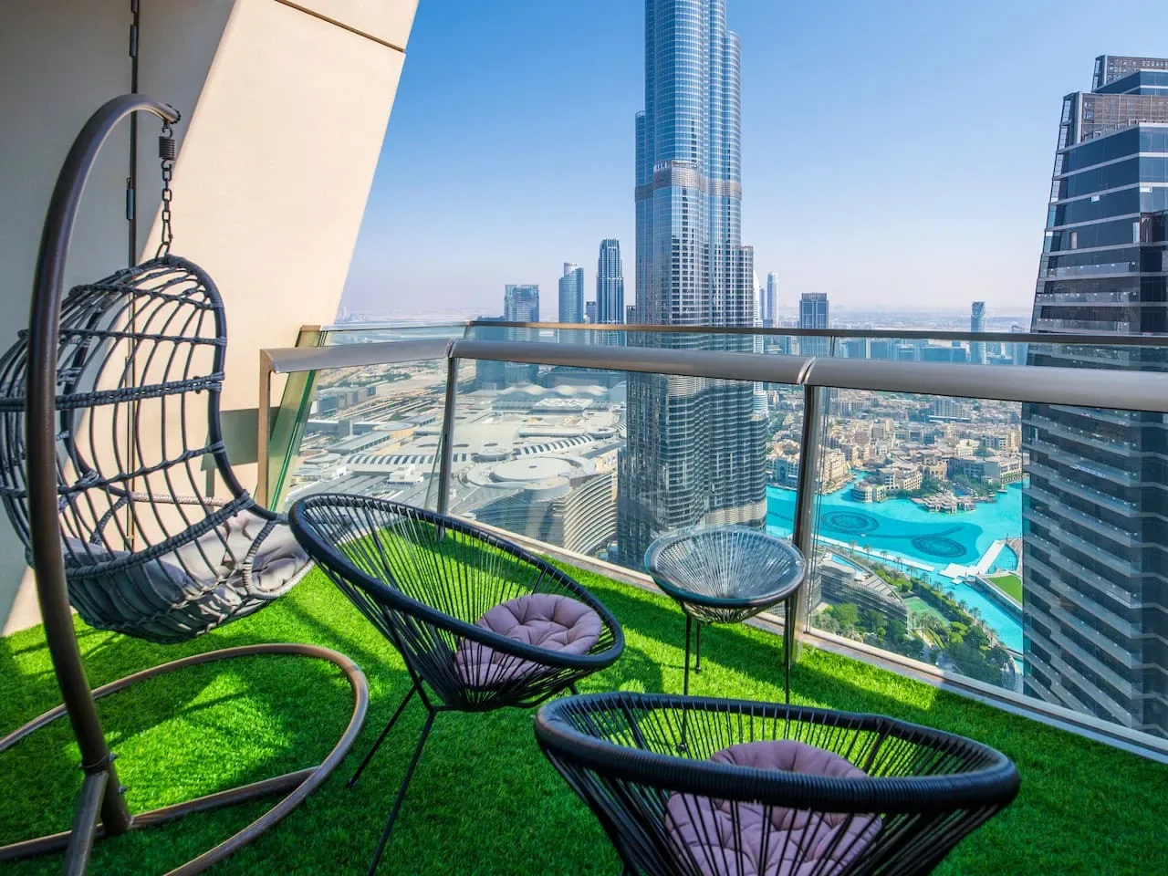 A balcony seating area overlooks a city skyline and a turquoise pool.