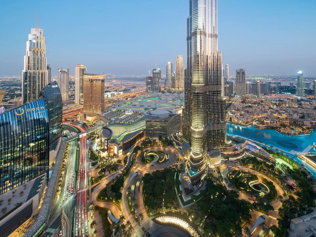 A city skyline at dusk features a tall central tower and surrounding buildings.