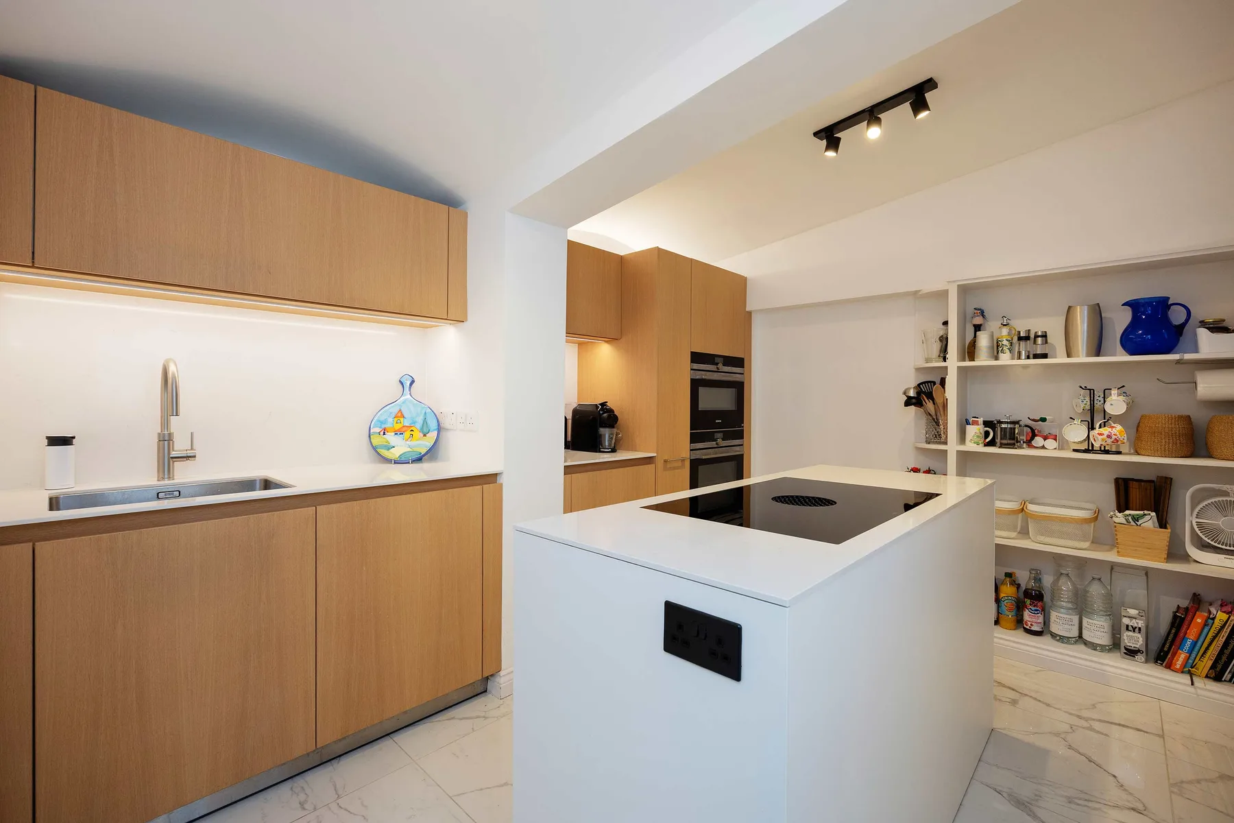 Una cocina moderna con una isla central y estanterías abiertas.