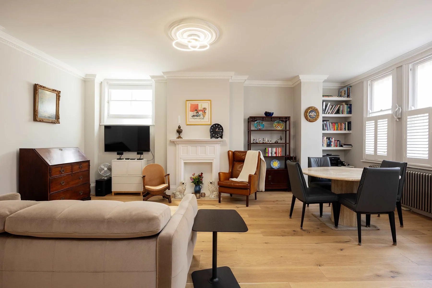 Una sala luminosa con asientos, una mesa de comedor y ventanas grandes.