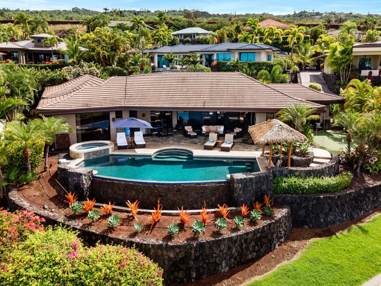 Un entorno tropical con piscina, asientos de descanso y abundante vegetación.