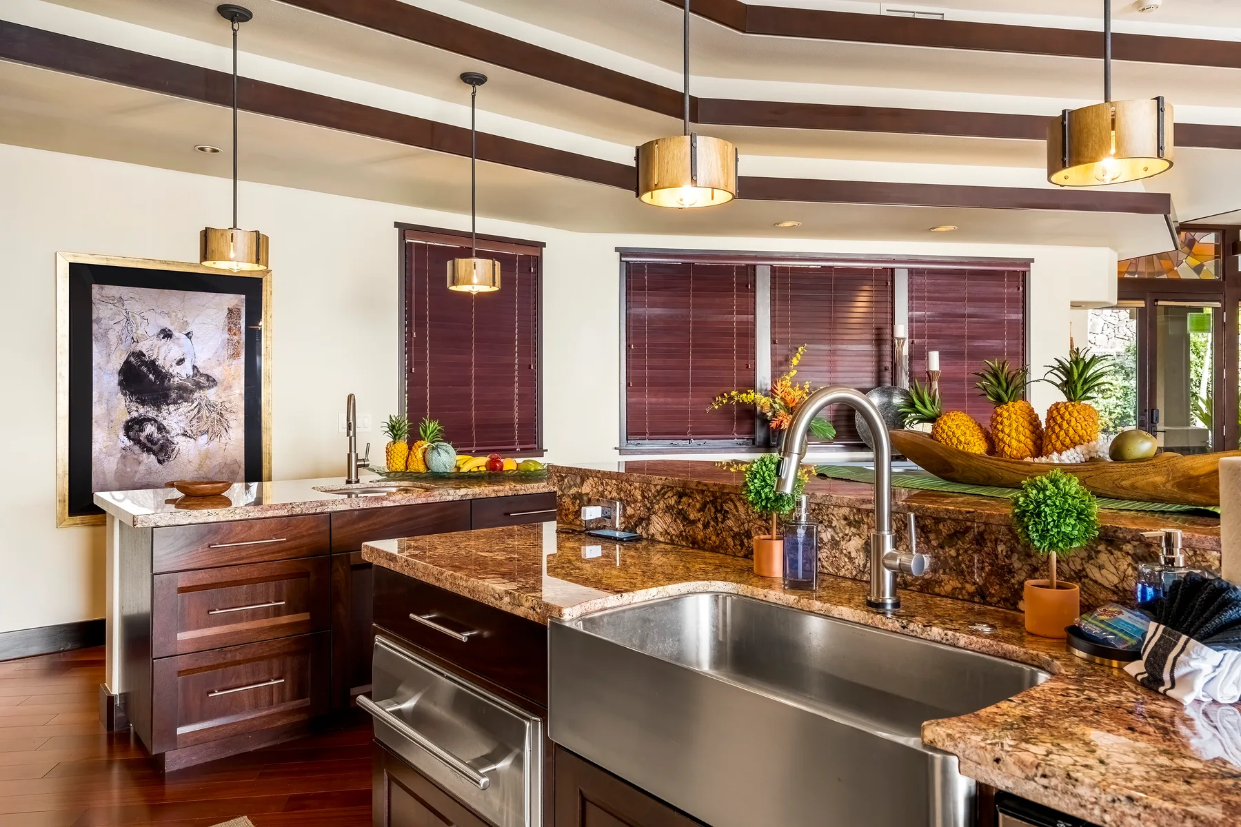 Una cocina con una isla grande, un fregadero de acero inoxidable y persianas oscuras.