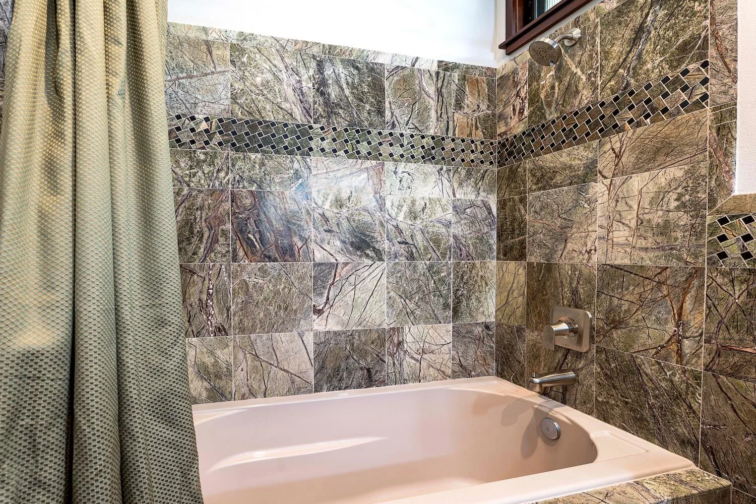 Un baño con bañera y paredes revestidas de azulejos.