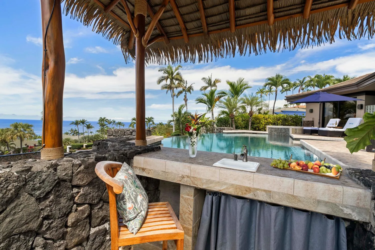 Un bar cubierto junto a la piscina da a una piscina y palmeras.