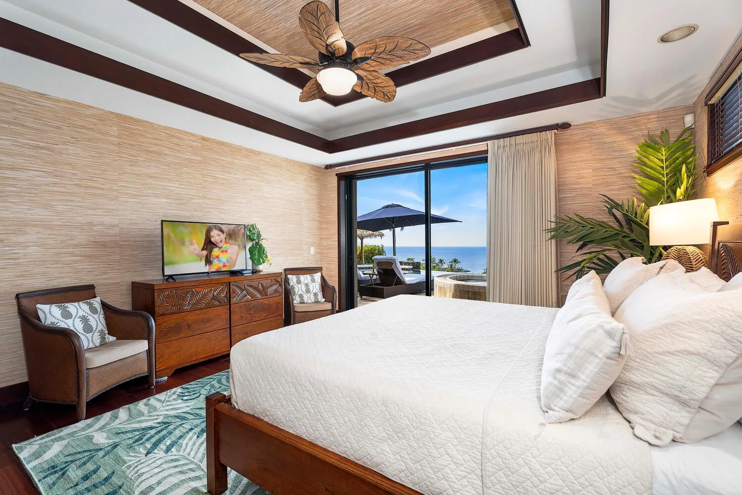 Un dormitorio con una cama blanca, muebles de madera y una vista a través de puertas corredizas de vidrio.