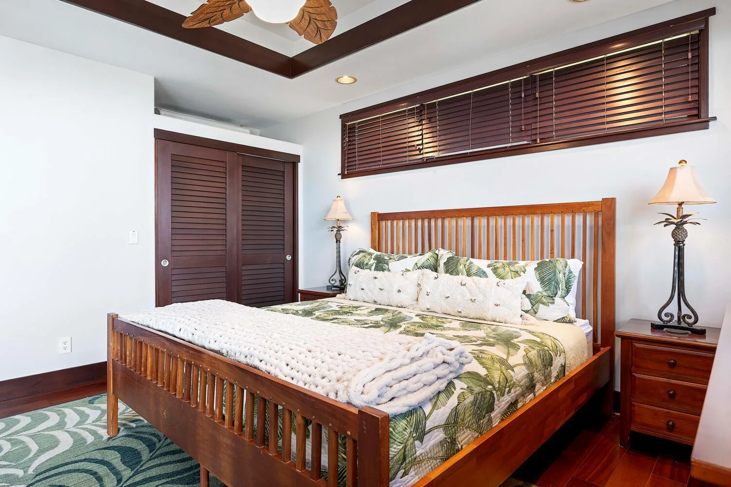 Un dormitorio con una cama de madera, ropa de cama estampada y persianas oscuras.