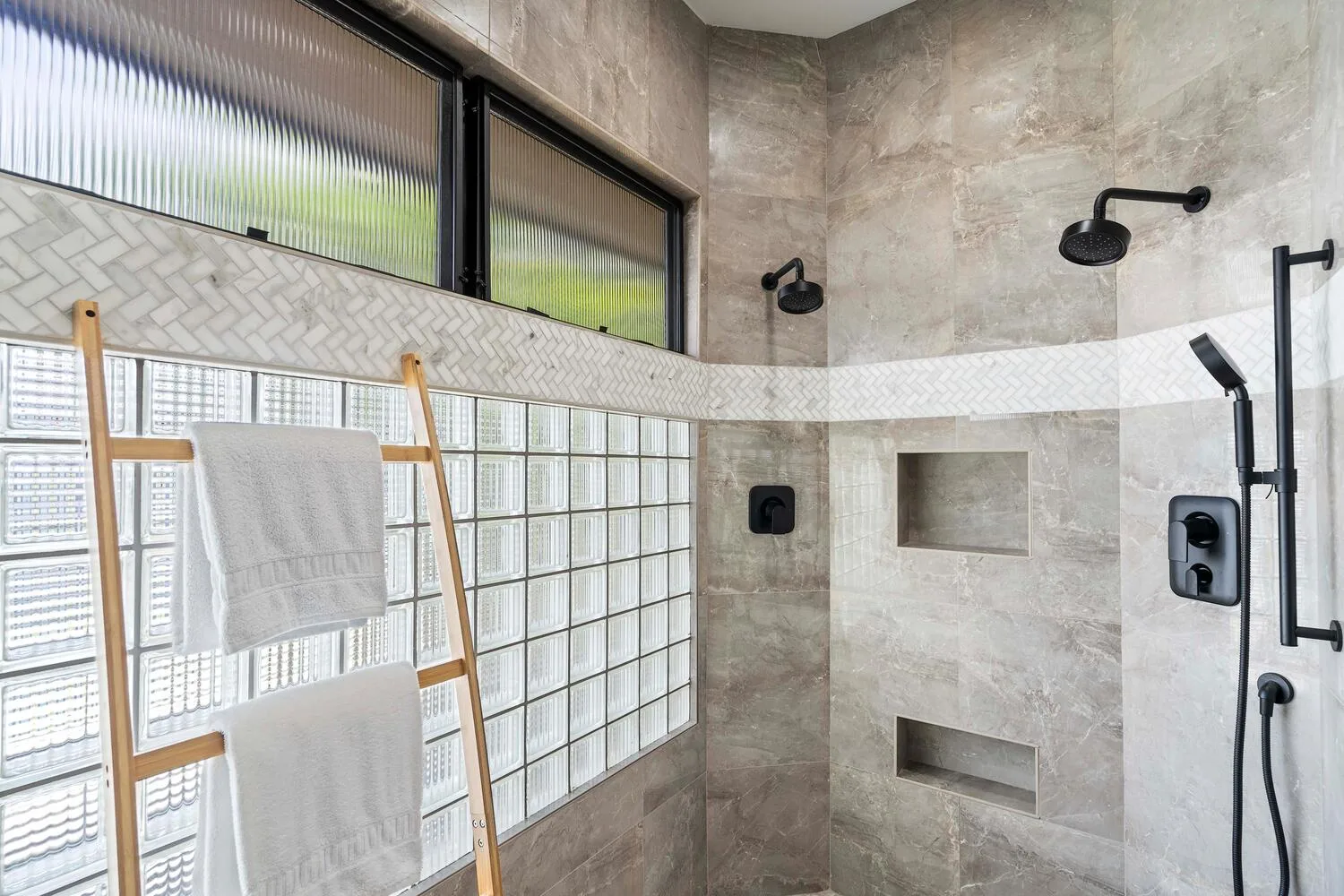 Un baño revestido de azulejos, con una pared de bloques de vidrio y accesorios de ducha.