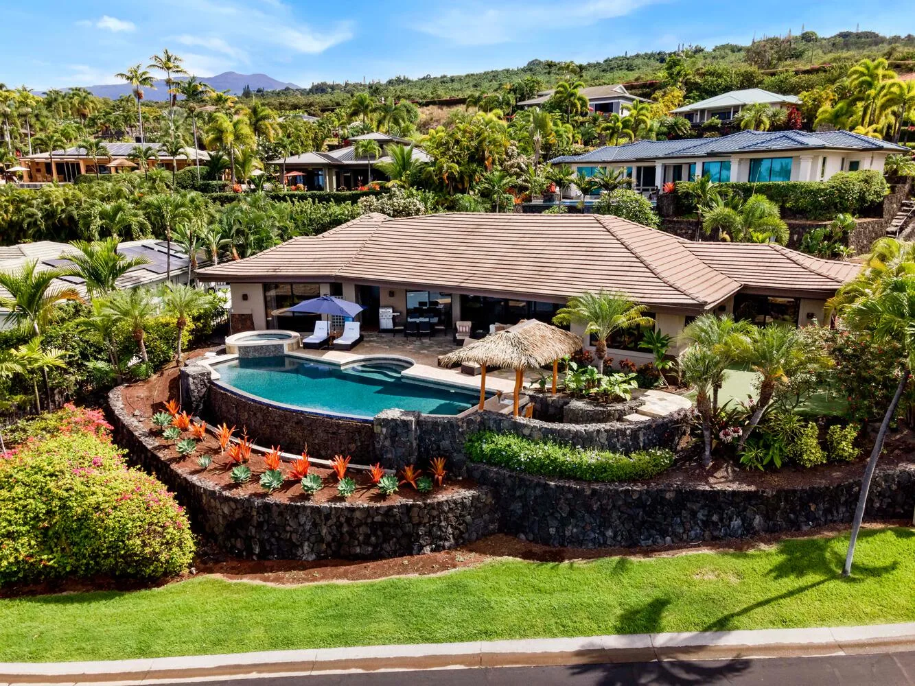 Una villa tropical da a una piscina rodeada de exuberante vegetación.