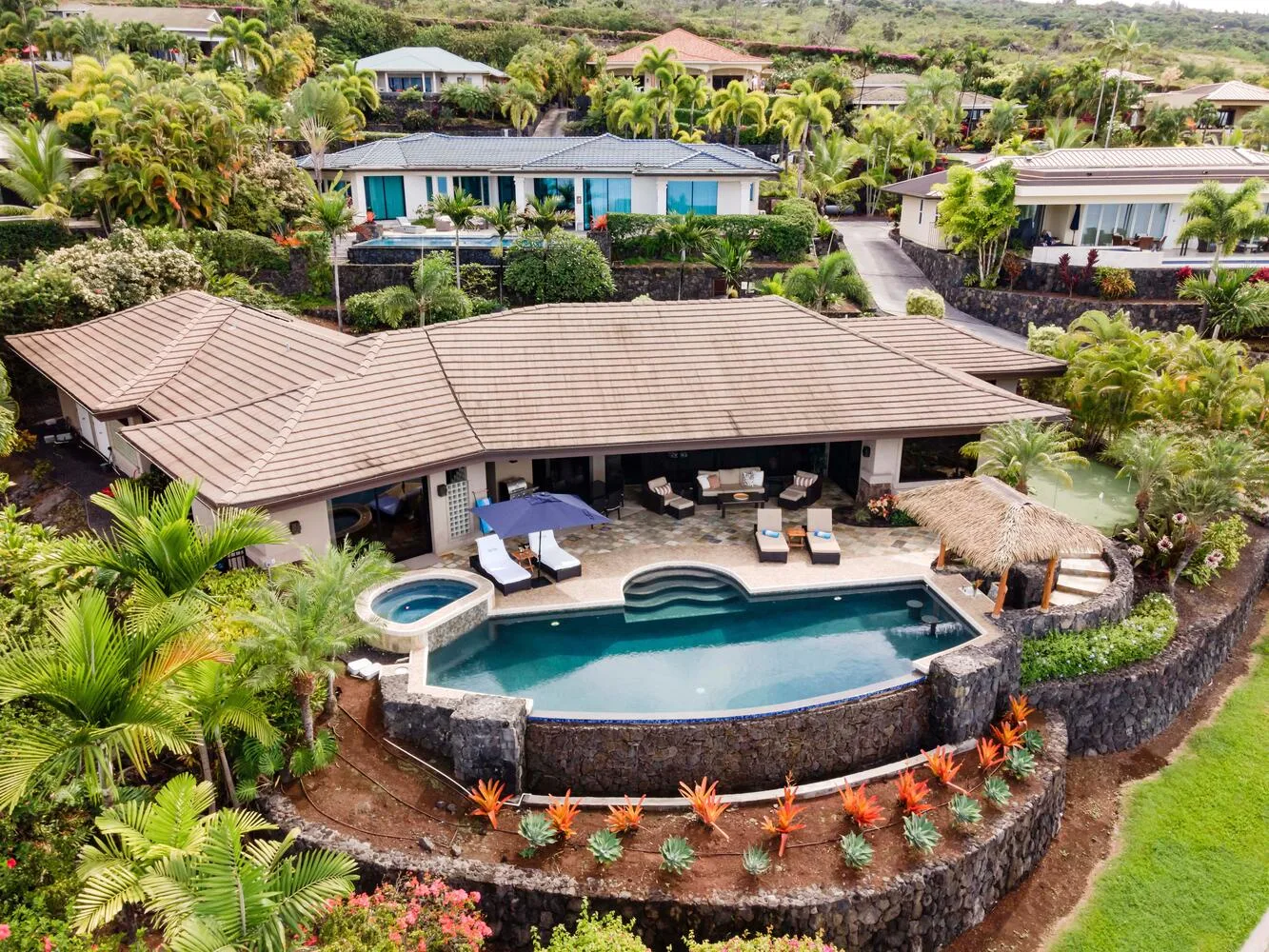 Vista aérea de un edificio tipo resort con piscina y vegetación alrededor.