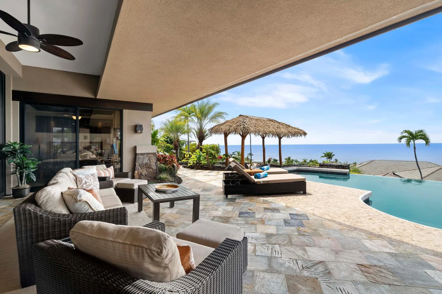 Un patio cubierto con asientos exteriores da a una piscina y al mar.