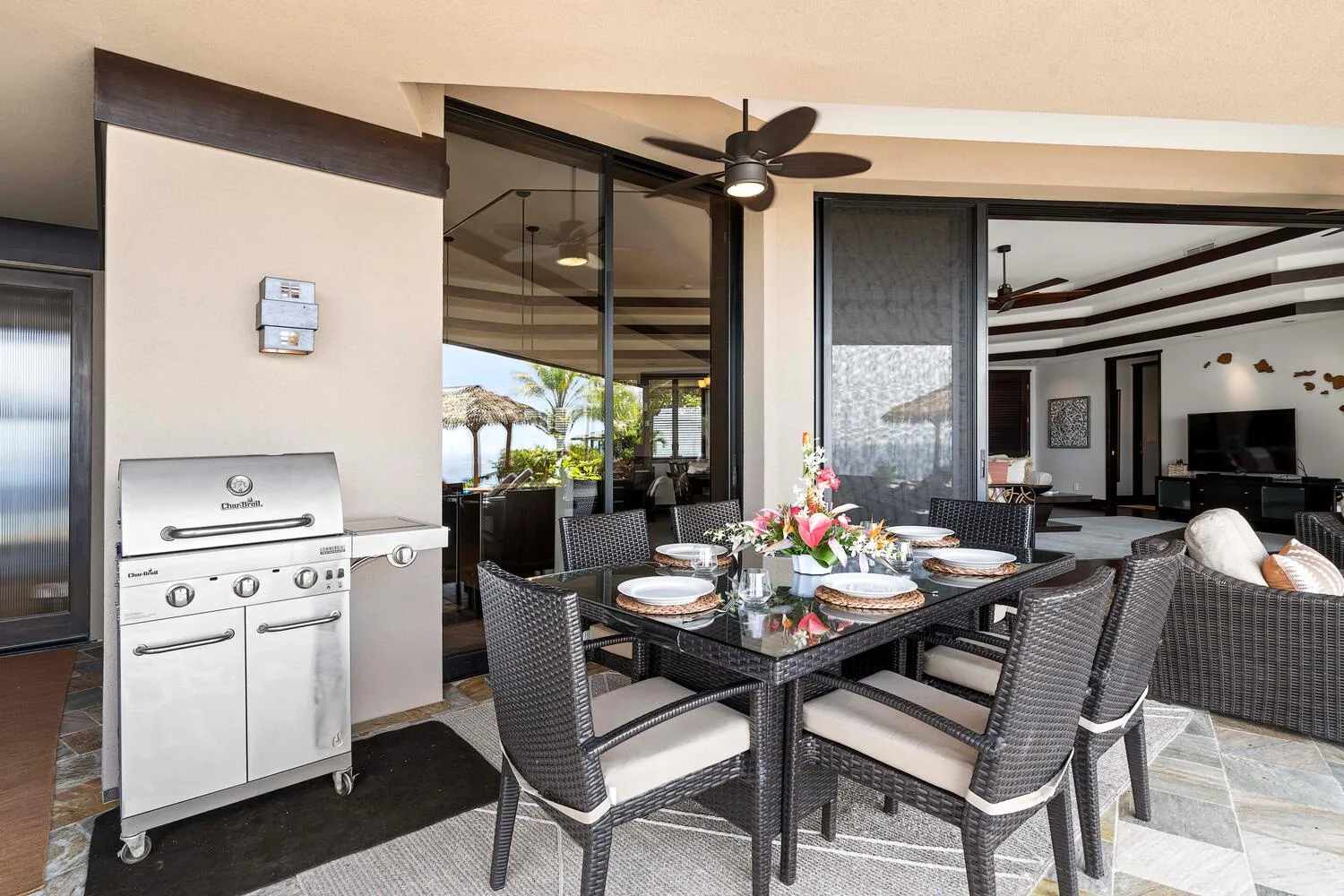 Un comedor cubierto en el patio tiene una mesa, asientos exteriores y una parrilla.