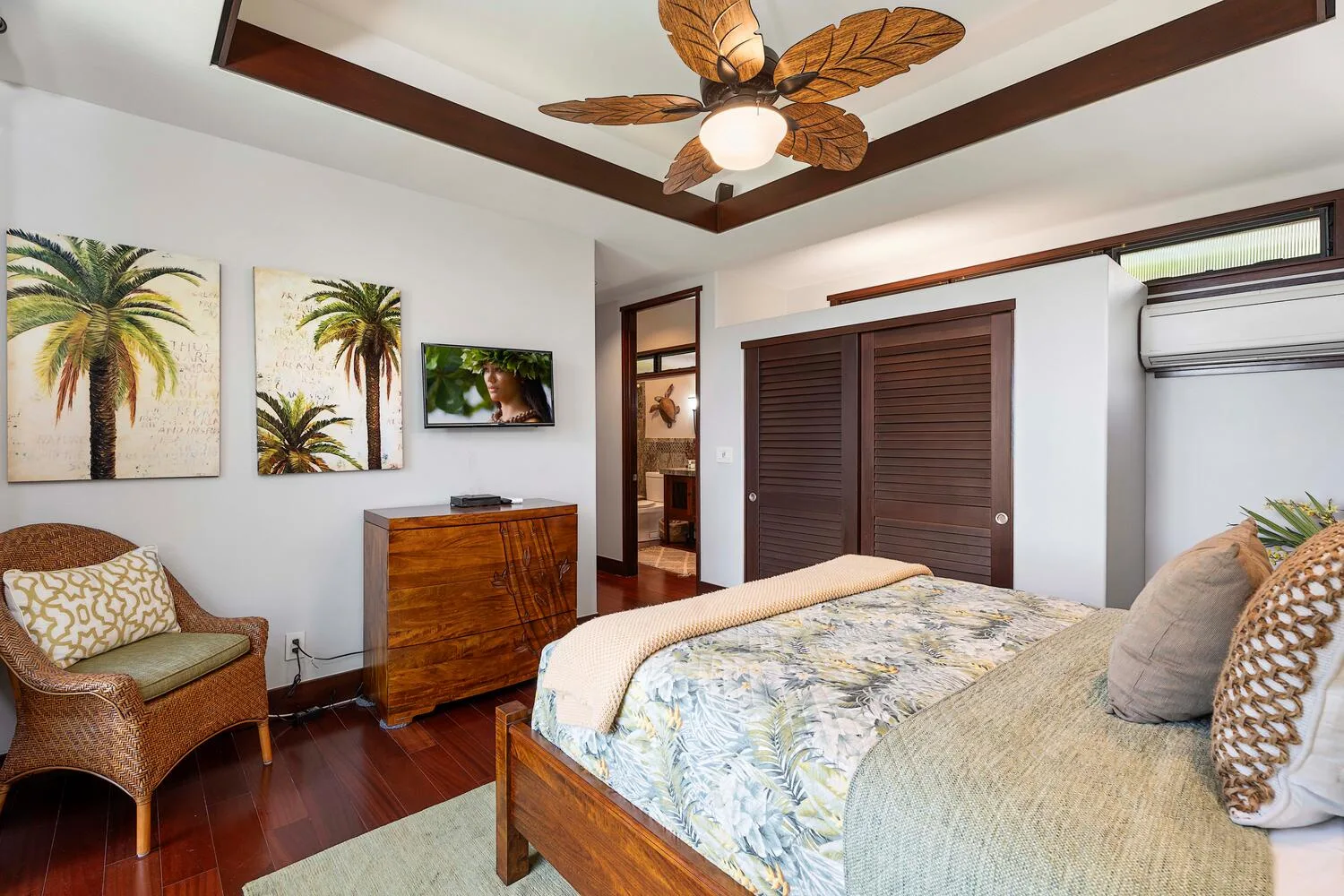Un dormitorio con una cama, una silla de mimbre y cuadros de palmeras en la pared.