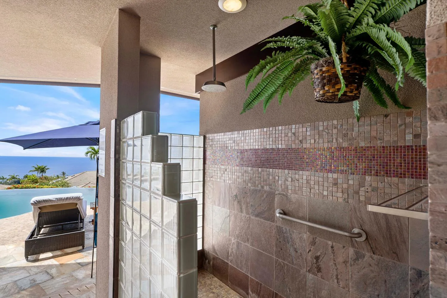 Una zona de ducha con azulejos da a un patio con vistas al agua.