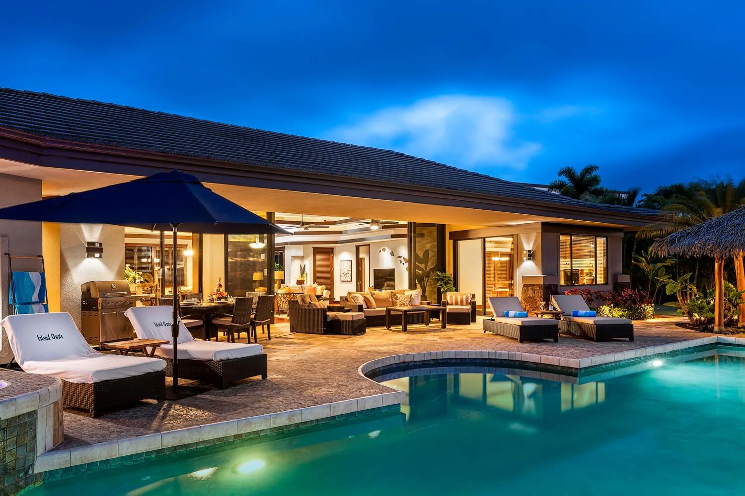 Una piscina exterior junto a una casa moderna con una zona de estar cubierta.