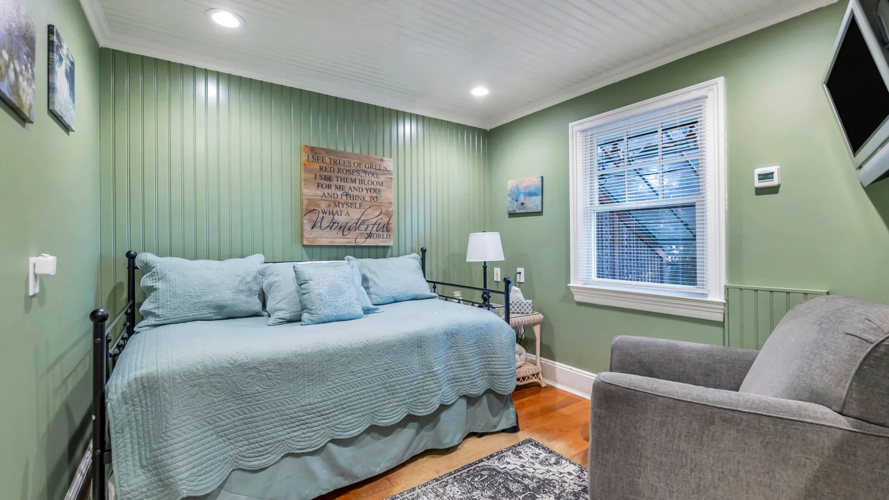A bedroom with a bed, a window, and an upholstered chair.