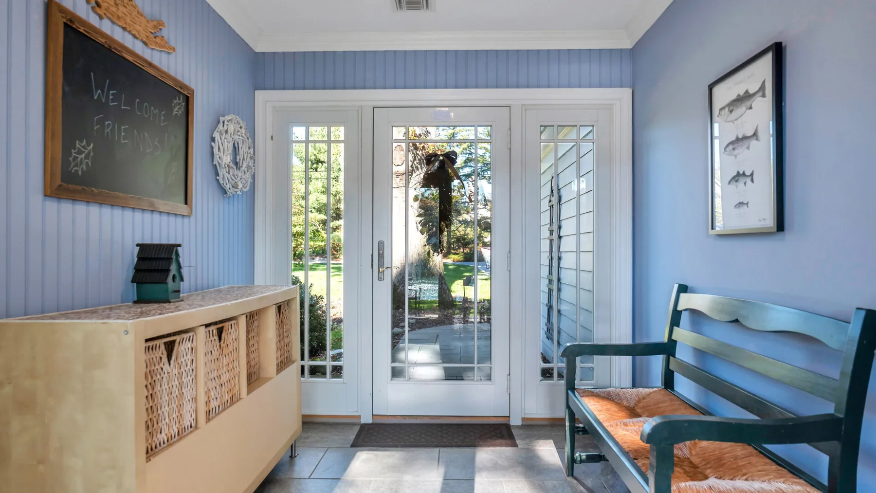 A bright entryway with glass doors and a wooden bench.