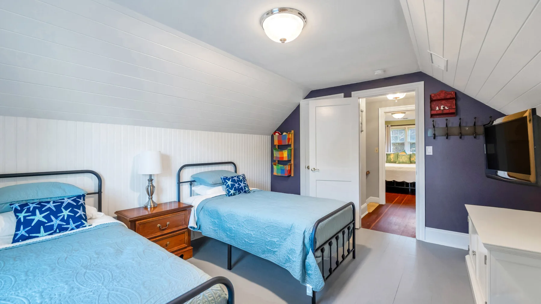 A bedroom with two beds covered in blue bedding.