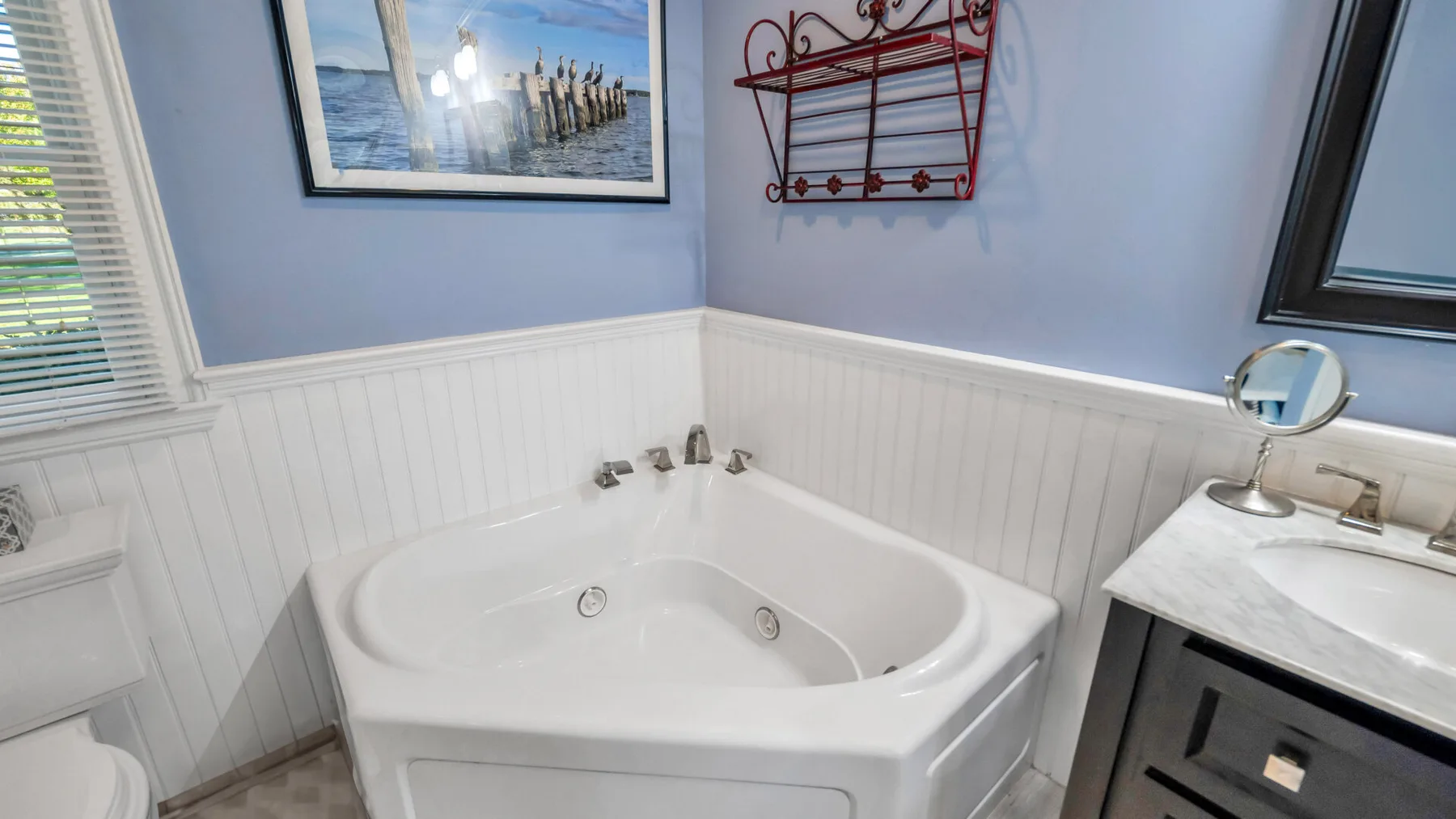 A bathroom with a corner bathtub and a vanity beside it.