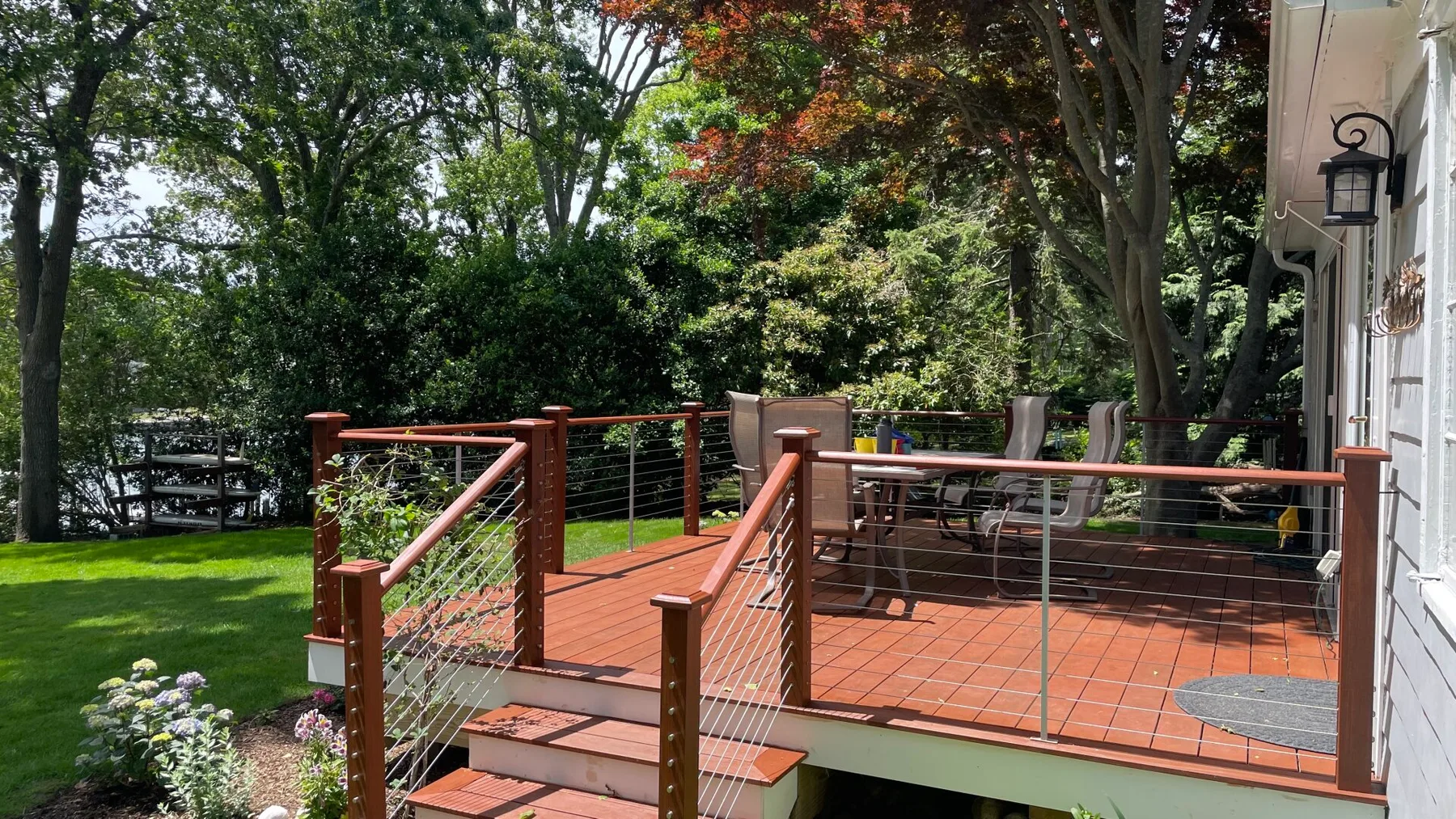 An outdoor patio with a table and chairs overlooks a green garden.