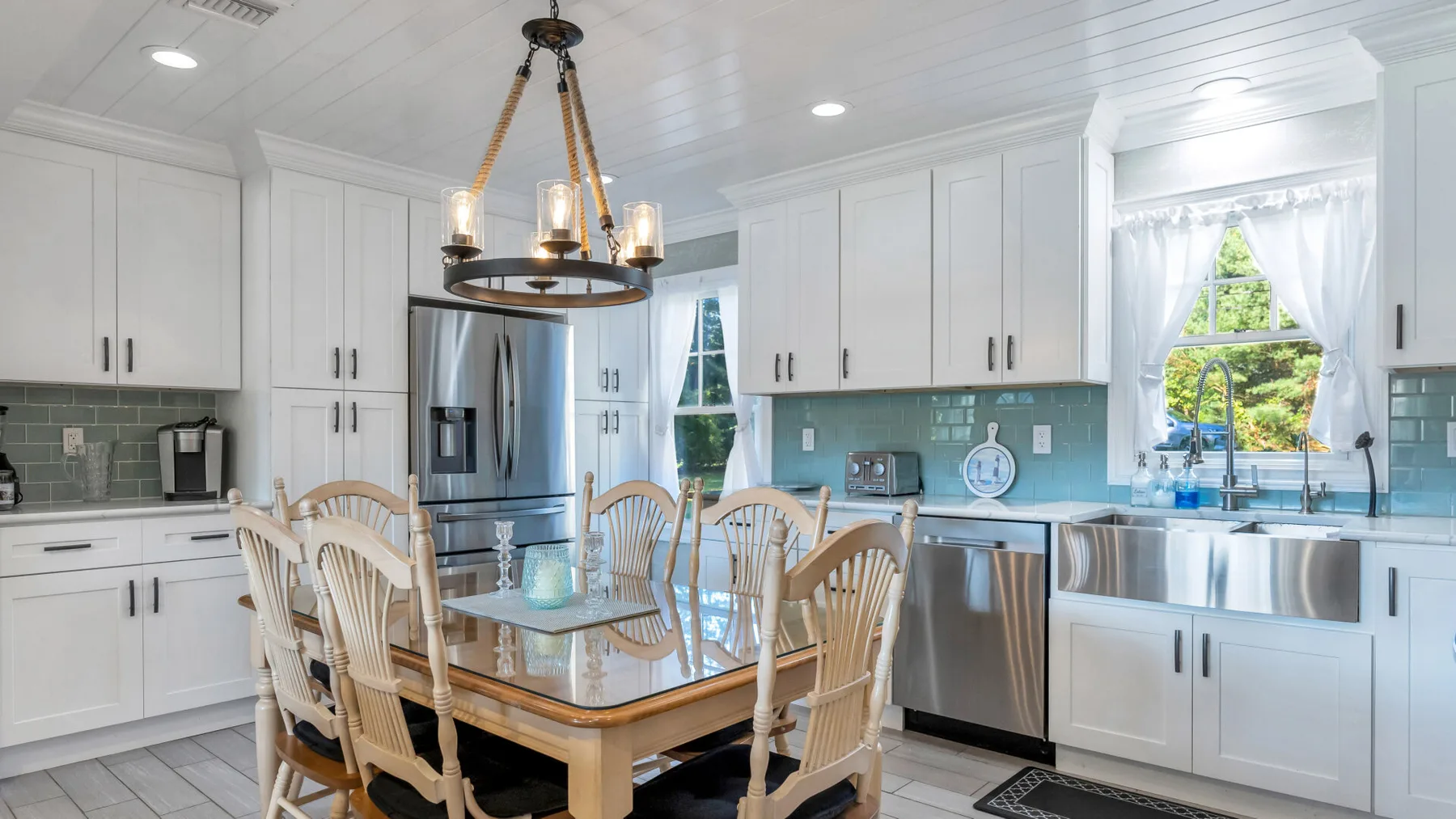 A bright kitchen with white cabinetry, a large island, and a dining table.