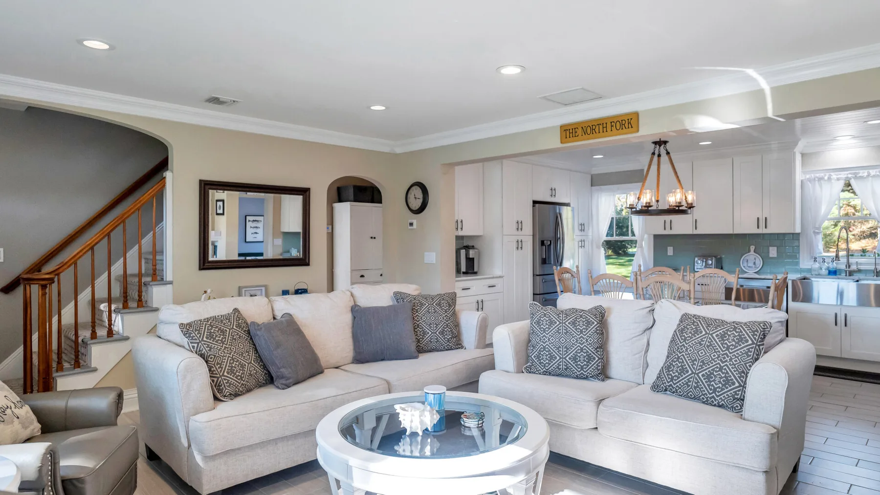 A bright living room with an L-shaped sofa and a dining area beyond.