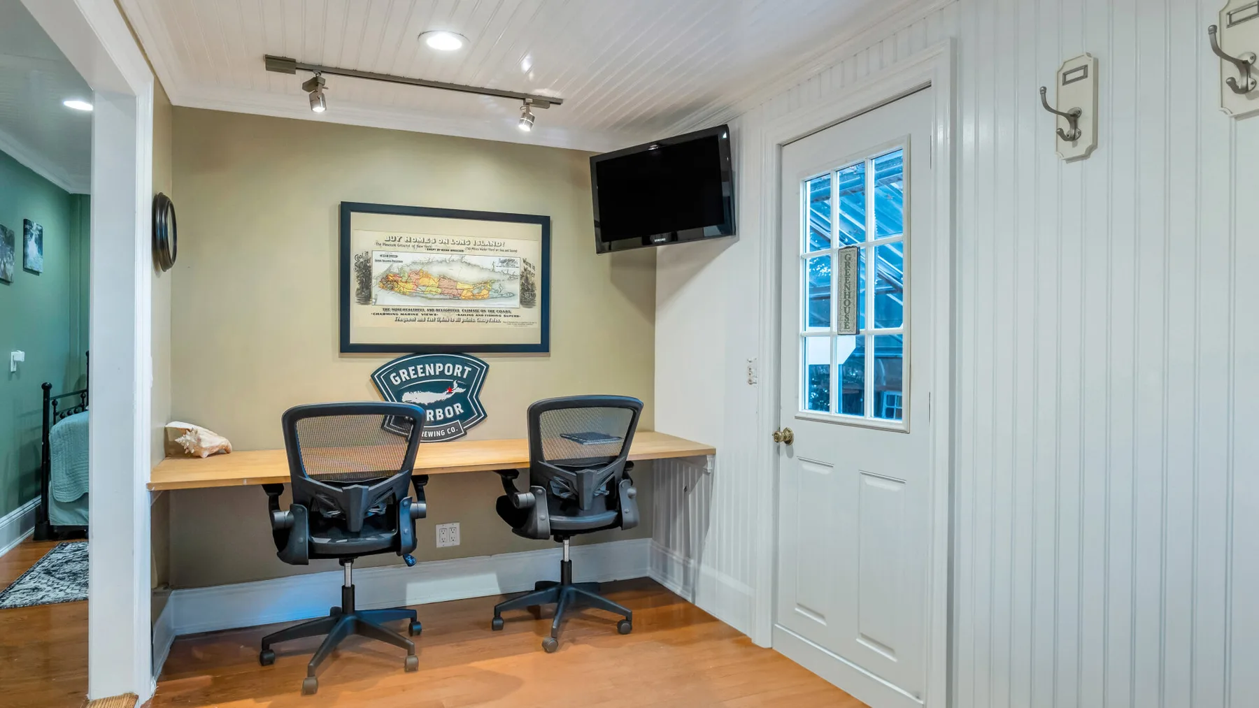 A small office with a desk and two chairs beside a white door.