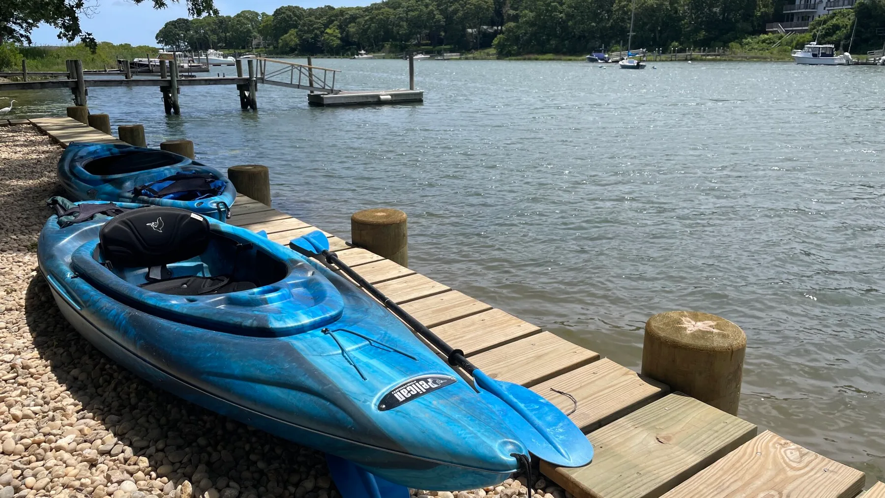 Blue kayaks rest beside a wooden dock along a calm river.