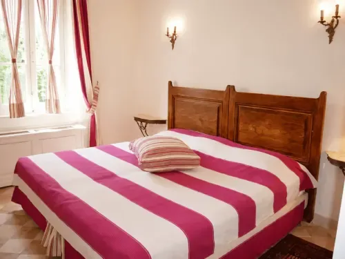 Bright double room with striped bedding and a garden view.