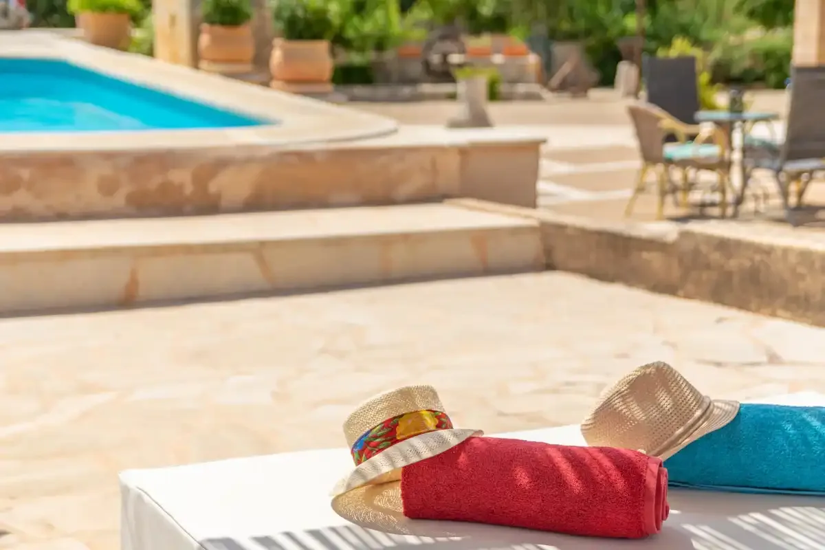Una toalla roja y sombreros de sol están junto a una piscina.