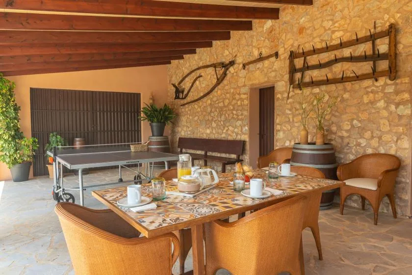 Un patio cubierto de piedra tiene una mesa de comedor y una mesa de ping-pong.