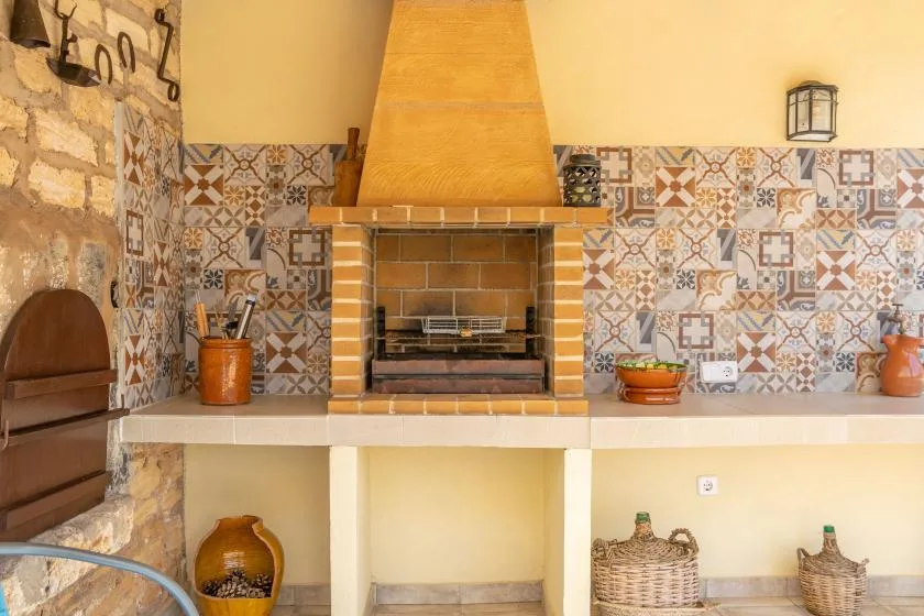 Una zona de cocina exterior con azulejos tiene una parrilla de ladrillo y una encimera.