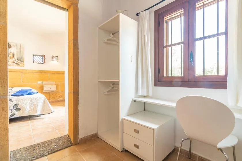 Una habitación luminosa con una ventana, un escritorio pequeño y una silla.