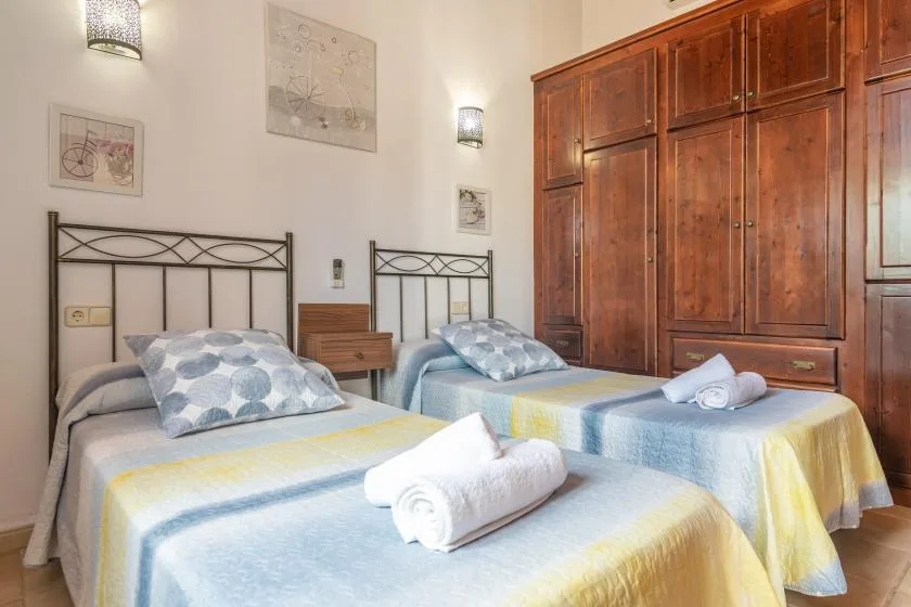 Un dormitorio con dos camas, ropa de cama colorida y un gran armario de madera.