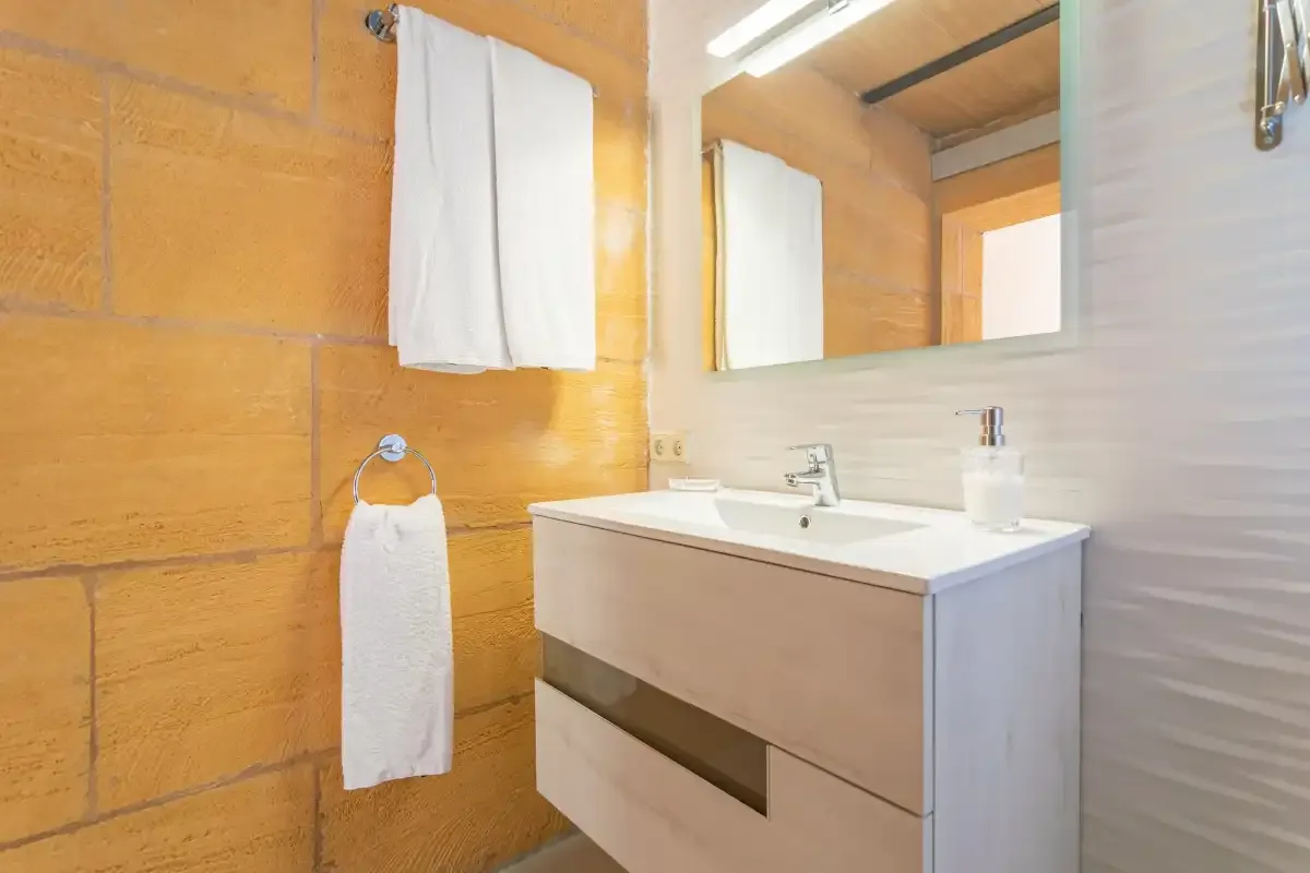 Un lavabo de baño con espejo junto a una pared texturizada.